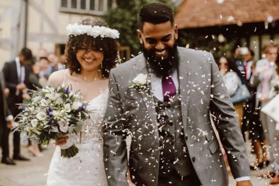 man and wife walking outside after just getting married with fake snow thrown at then for the beautiful photograph