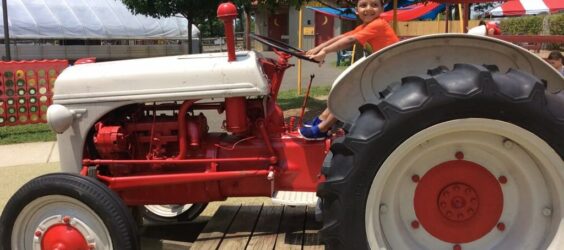 child sitting on big red tractor at summer camp