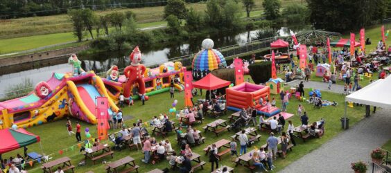 big family event on a field with tables and bounce houses for children