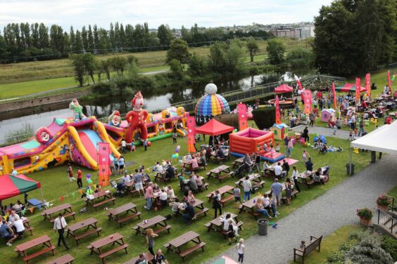 big family event on a field with tables and bounce houses for children