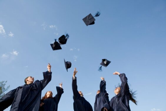 high school graduates throwing their hats in the air