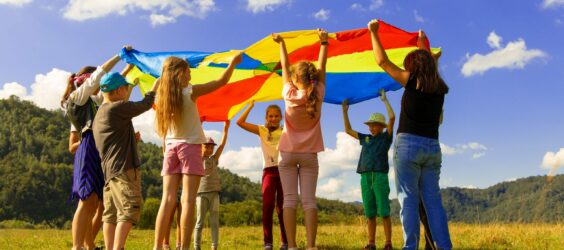 kids standing in a cirlce with a round color wheel above there heads at summer camp