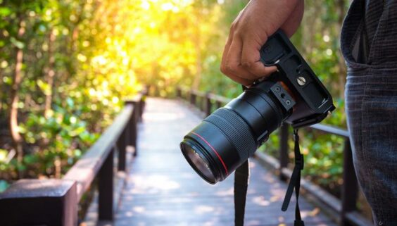 photographer holding camera while walking on board walk